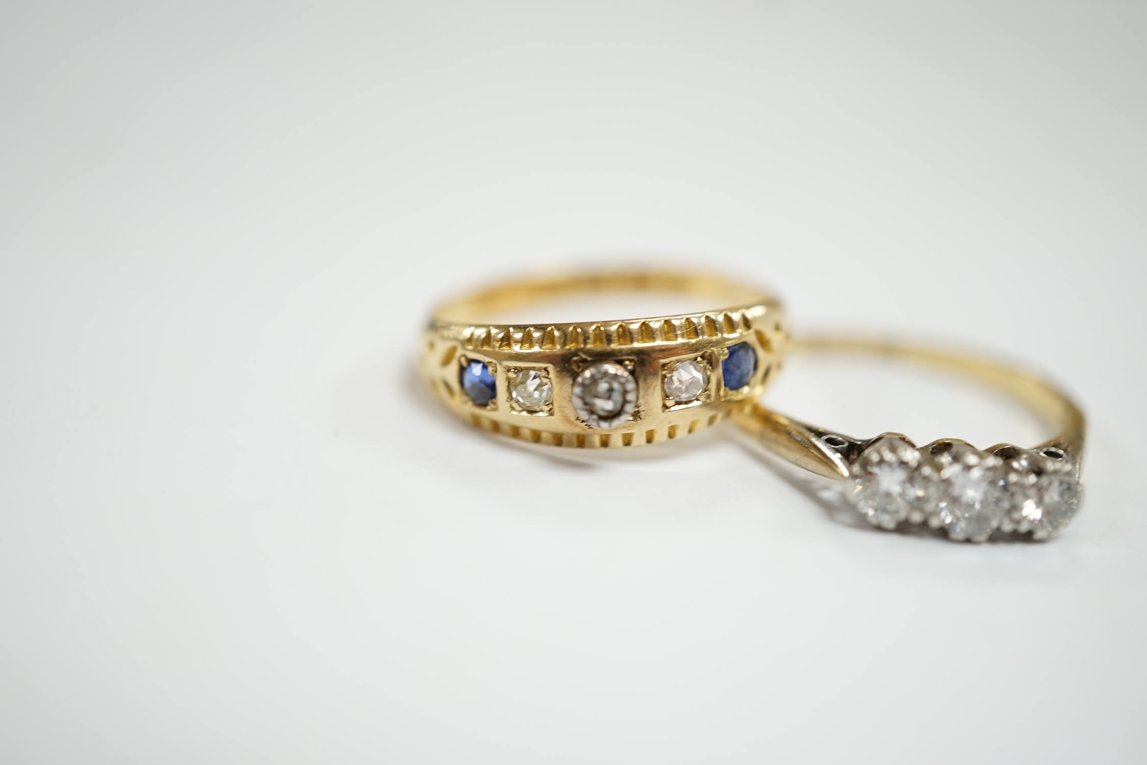 An 18ct, plat and three stone diamond set ring, size K and a late Victorian 18ct gold three stone diamond and two stone sapphire set ring, size K, gross weight 4.1 grams.
